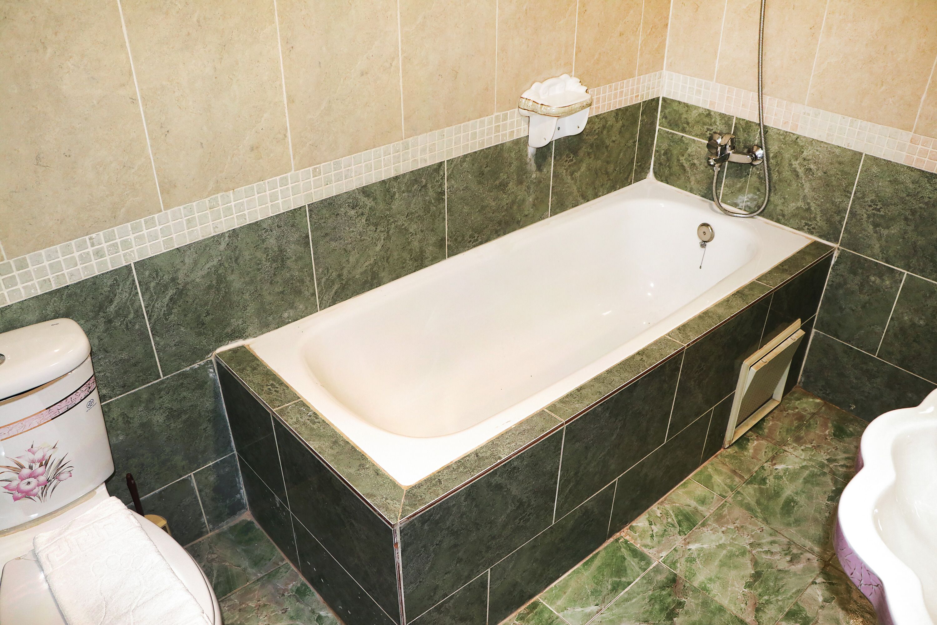 A bathroom with a bathtub, a toilet, and a shower area.