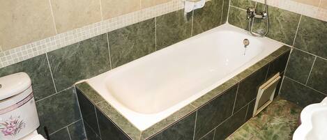 A bathroom with a bathtub, a toilet, and a shower area.