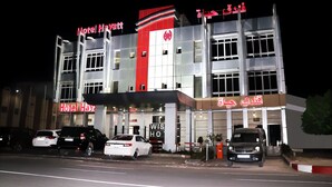 Un hotel de diseño moderno, con una llamativa decoración en rojo y blanco y varios espacios de estacionamiento al frente.