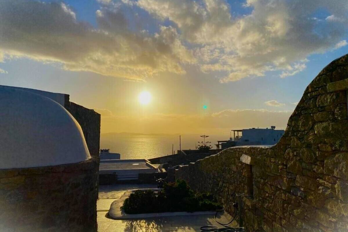 A stone wall and a building with a dome, overlooking a body of water during sunset.