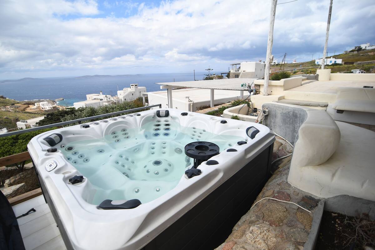 A hot tub on a rooftop with a view of the sea and buildings.