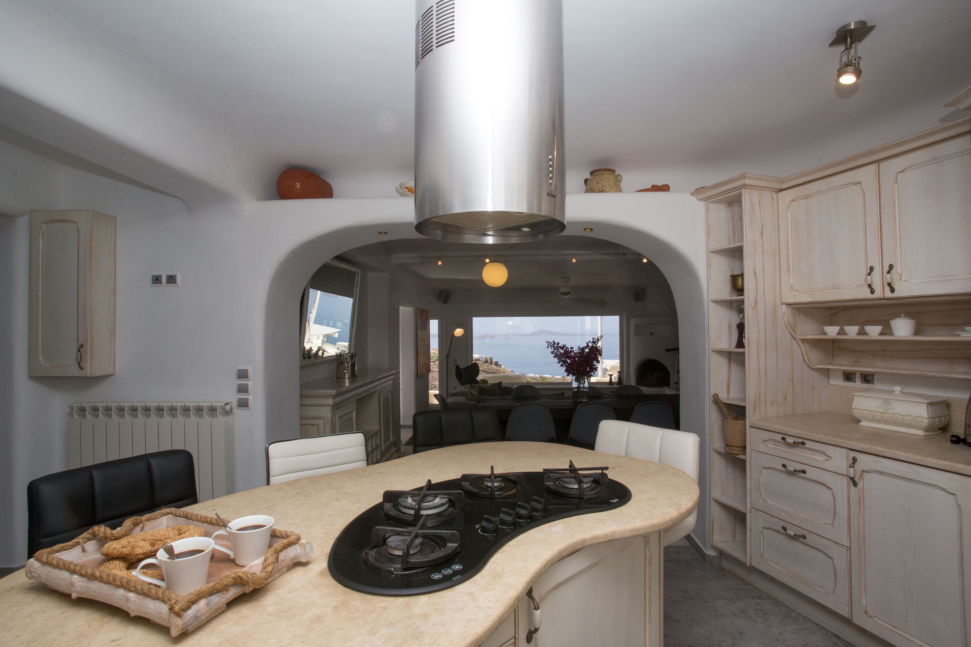 Une cuisine moderne dotée d’un îlot central, de meubles de rangement intégrés et offrant une vue sur la mer.