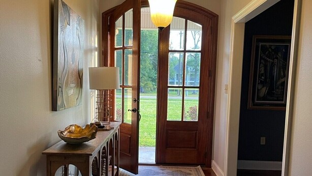 A hallway with a wooden door, a table with a lamp, and a hanging light fixture.