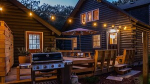 A wooden cabin with a barbecue area, outdoor seating, and string lights. - The Cabin - Unique OBX Stay, Huge Yard! (Kill Devil Hills)