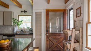 A kitchen with a wooden table, a sink, and a window. - The Cabin - Unique OBX Stay, Huge Yard! (Kill Devil Hills)