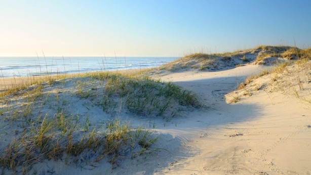 A sandy beach with dunes and sparse vegetation. - The Cabin - Unique OBX Stay, Huge Yard! (Kill Devil Hills)