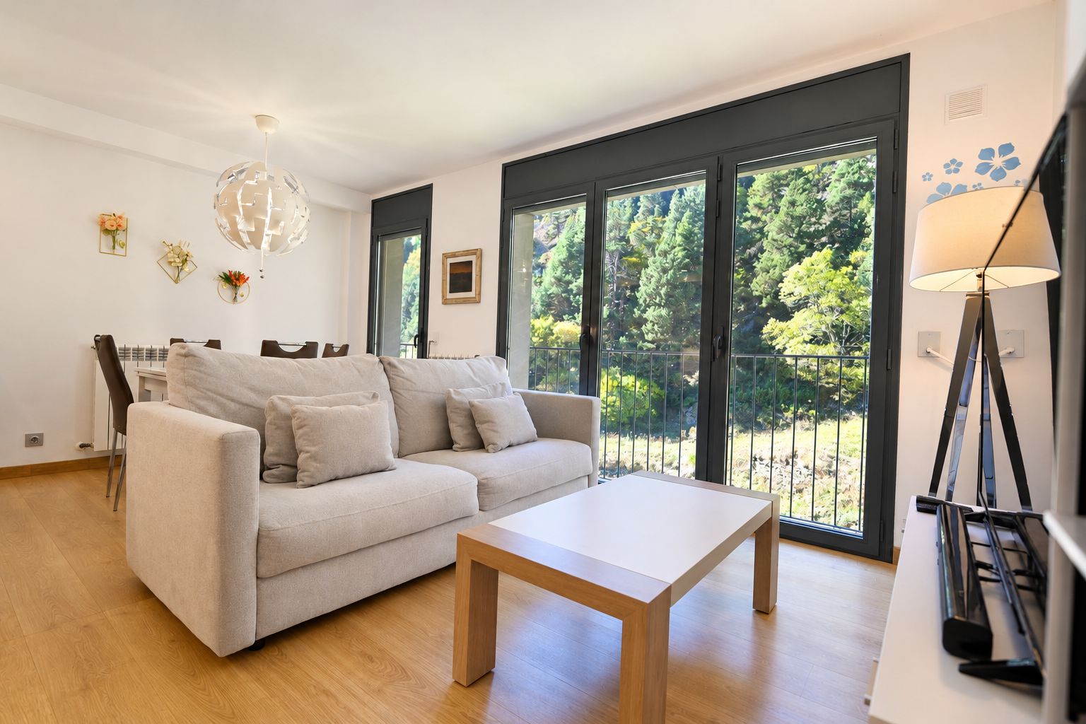 Een moderne woonkamer met een bank, salontafel en een eethoek met stoelen.
