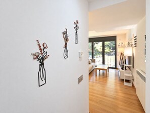 A modern interior with a wooden floor, a white wall with three black vases, a sofa, and a dining table.