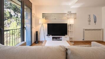Een moderne woonkamer met een grote flatscreen televisie, een vloerlamp en een bank.