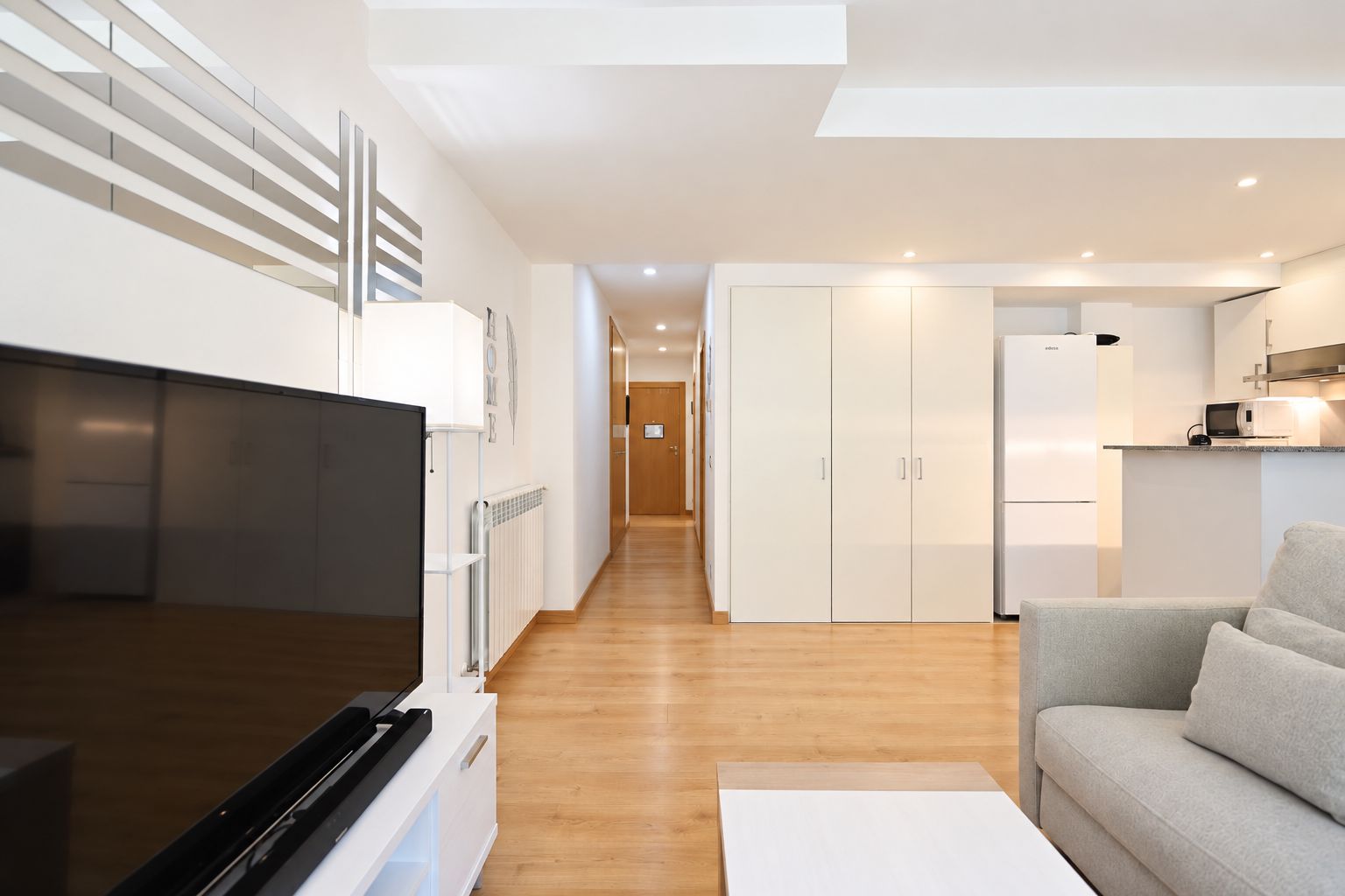 Un appartement moderne équipé d’une télévision, d’une kitchenette et d’un canapé.