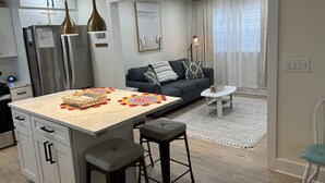 A modern kitchen with a central island, bar stools, a sofa, and a dining table. - Sandy Feet Retreat *A top stay in the Crest* (Wildwood Crest)