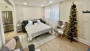 A modern bedroom with a bed, a small desk, a chair, a Christmas tree, and a refrigerator. - Sandy Feet Retreat *A top stay in the Crest* (Wildwood Crest)