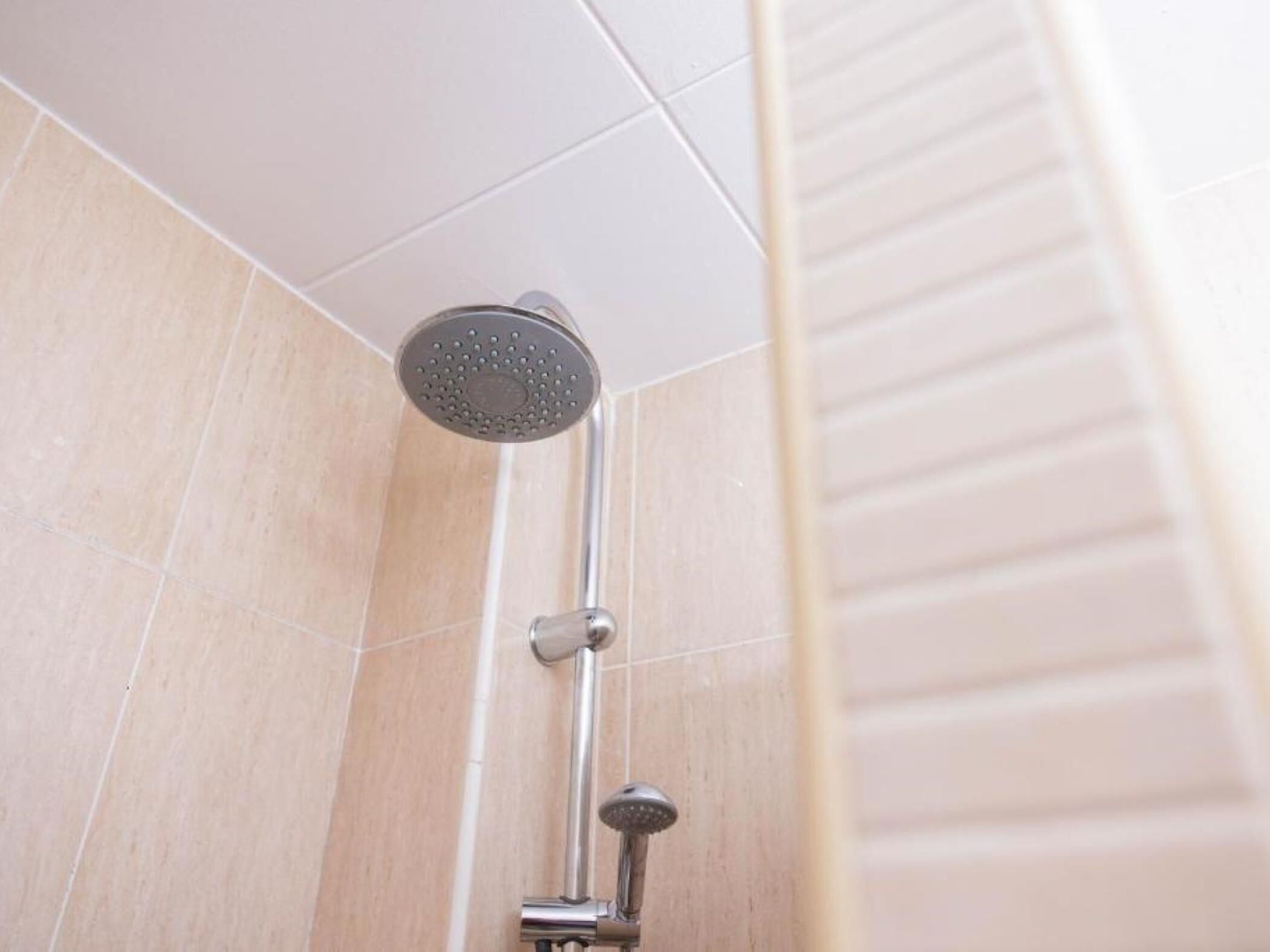 A showerhead mounted on a wall with a vertical handle.