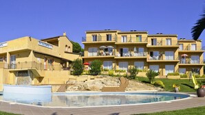 Un hotel con piscina, varios balcones y fachada de piedra.