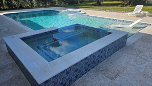 A rectangular swimming pool with a tiled border and a smaller section with a different tile pattern. - River Bank Hideaway, "Go With The Flow" RIVERFRONT 3 Acres- "Heated Pool/Spa" (LaBelle)