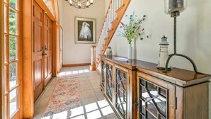 A hallway with wooden doors, a chandelier, a vase with flowers, and a lamp. - River Bank Hideaway, "Go With The Flow" RIVERFRONT 3 Acres- "Heated Pool/Spa" (LaBelle)