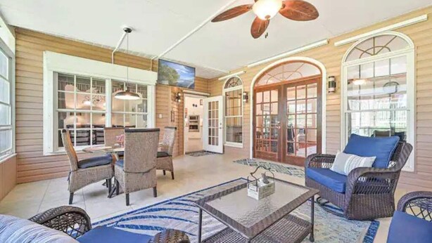 A spacious indoor area with wicker furniture, a ceiling fan, and large windows. - River Bank Hideaway, "Go With The Flow" RIVERFRONT 3 Acres- "Heated Pool/Spa" (LaBelle)
