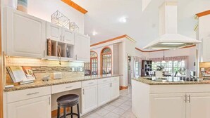 A modern kitchen with white cabinetry, a granite countertop, and a central island. - River Bank Hideaway, "Go With The Flow" RIVERFRONT 3 Acres- "Heated Pool/Spa" (LaBelle)
