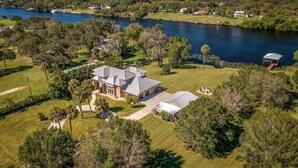 A large house with a spacious lawn and a lake view. - River Bank Hideaway, "Go With The Flow" RIVERFRONT 3 Acres- "Heated Pool/Spa" (LaBelle)