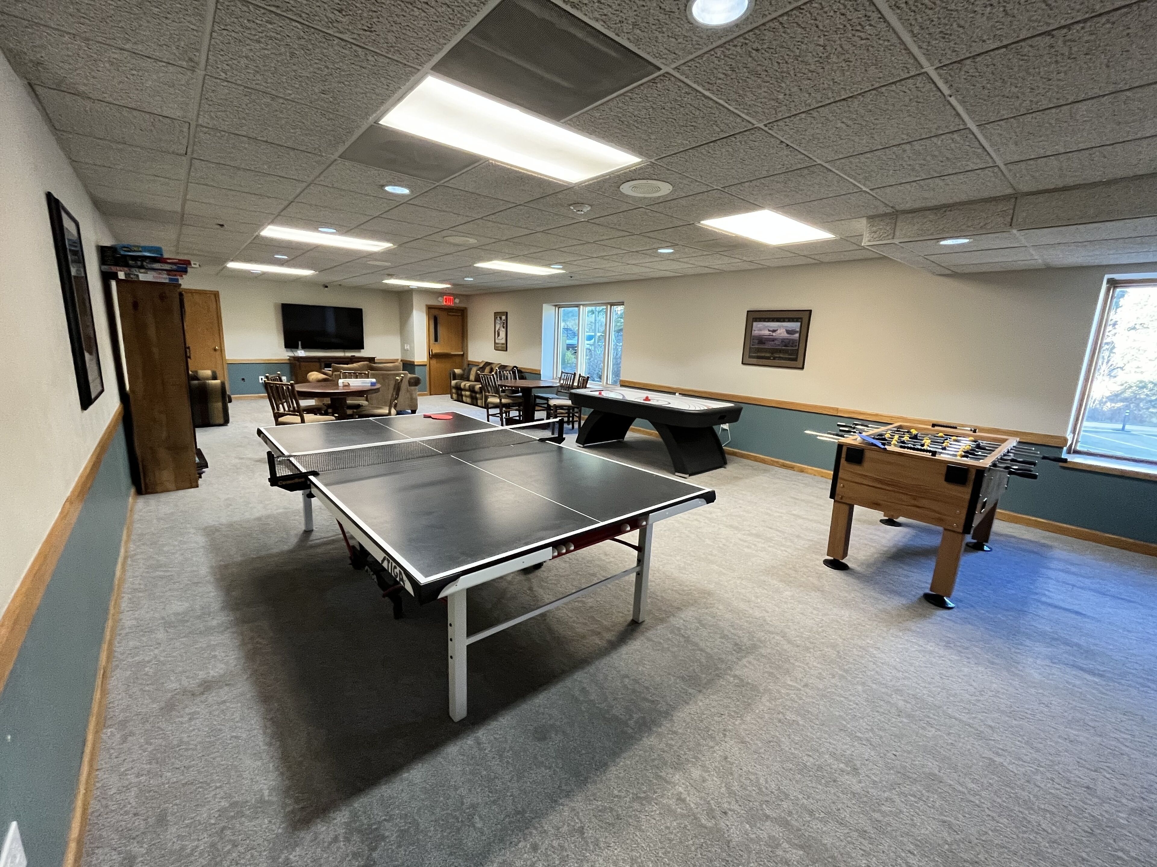 Una habitación con mesa de ping pong, mesa de fútbol de mesa y televisor.
