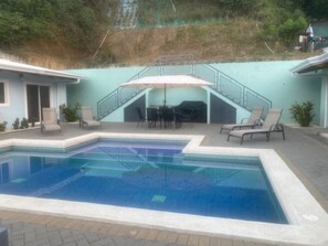 A swimming pool with a covered patio area, outdoor seating, and a staircase leading to a covered deck. - Beautiful new home located on the Central pacific near Playa Hermosa Beach! (Puntarenas)