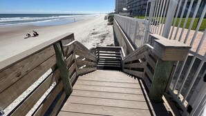 Eine Holztreppe führt zu einem Strand mit freiem Blick auf das Meer.