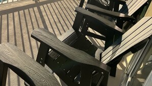 Een balkon met Adirondack-stoelen, met uitzicht op een zwembad en de oceaan.