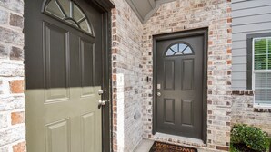 A house with two dark-colored doors, a brick exterior, and a welcome mat at the entrance. - *EADO Urban Escape, Gated Home, Sleeps 4* (Houston)