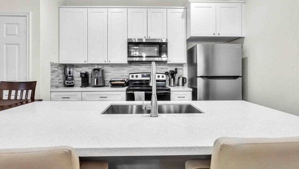 A modern kitchen with white cabinets, stainless steel appliances, and a central island with a sink. - *EADO Urban Escape, Gated Home, Sleeps 4* (Houston)