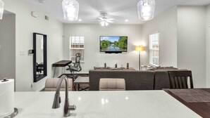 A modern kitchen with a central island, a dining area with a TV, and a seating arrangement. - *EADO Urban Escape, Gated Home, Sleeps 4* (Houston)