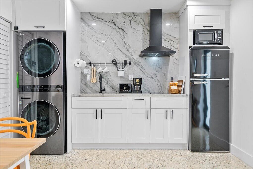 A modern kitchen with a washing machine, microwave, and refrigerator.