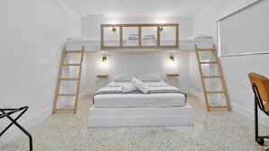 Une chambre avec un lit superposé, une échelle en bois, un matelas blanc et un miroir fixé au mur.