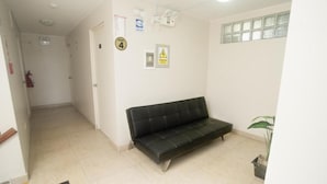 A hallway with a black sofa, a door labeled "PISO 4", a fire extinguisher, and a plant. - hospedaje sueños (Lima)