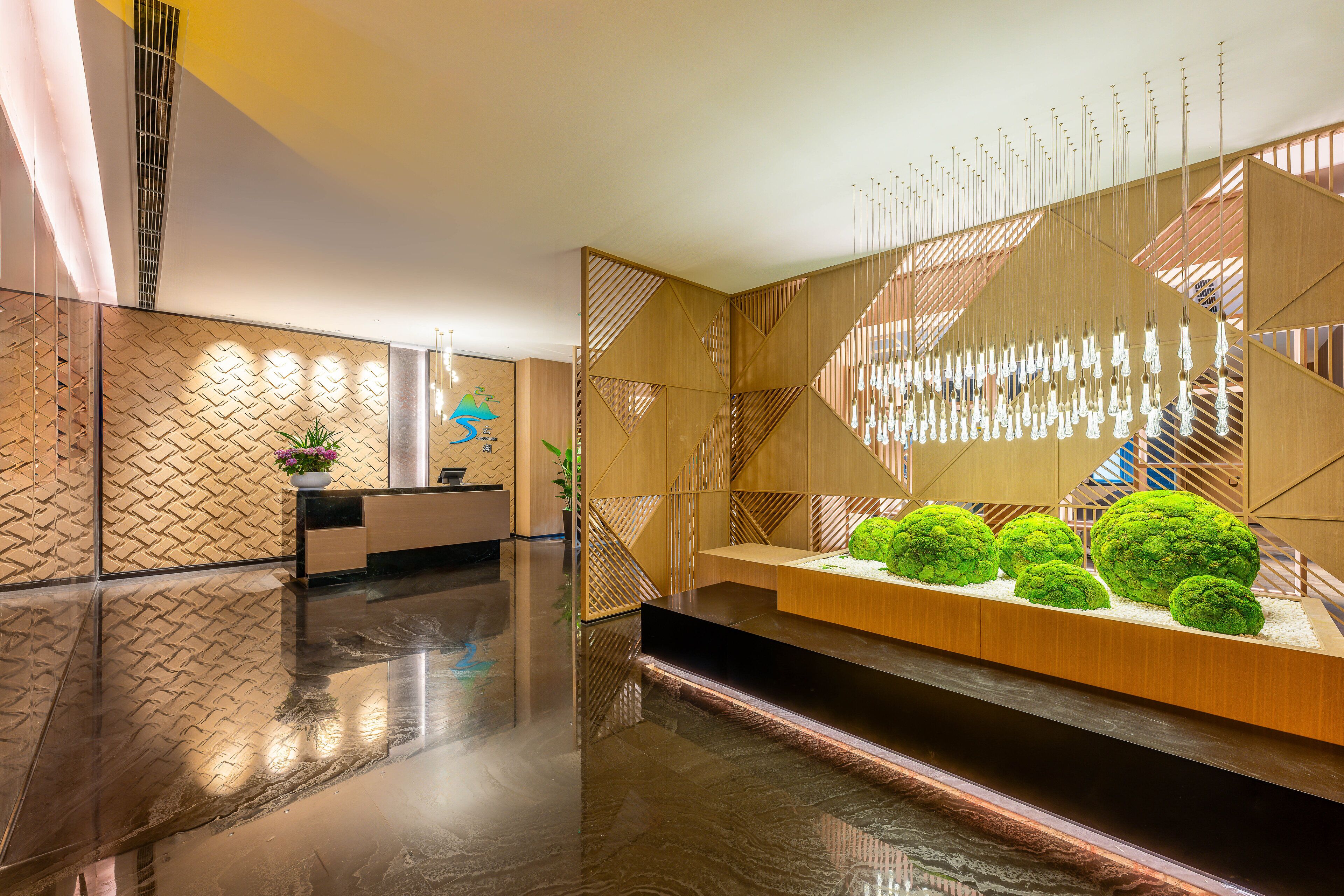 Un hall d’entrée moderne avec un sol ciré, un comptoir d’accueil et un espace détente agrémenté de plantes vertes.