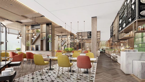 Interior moderno de restaurante con techos altos, vigas de madera a la vista y una escalera central. Mesas y sillas dispuestas para comer, con una zona de cocina visible a la derecha.