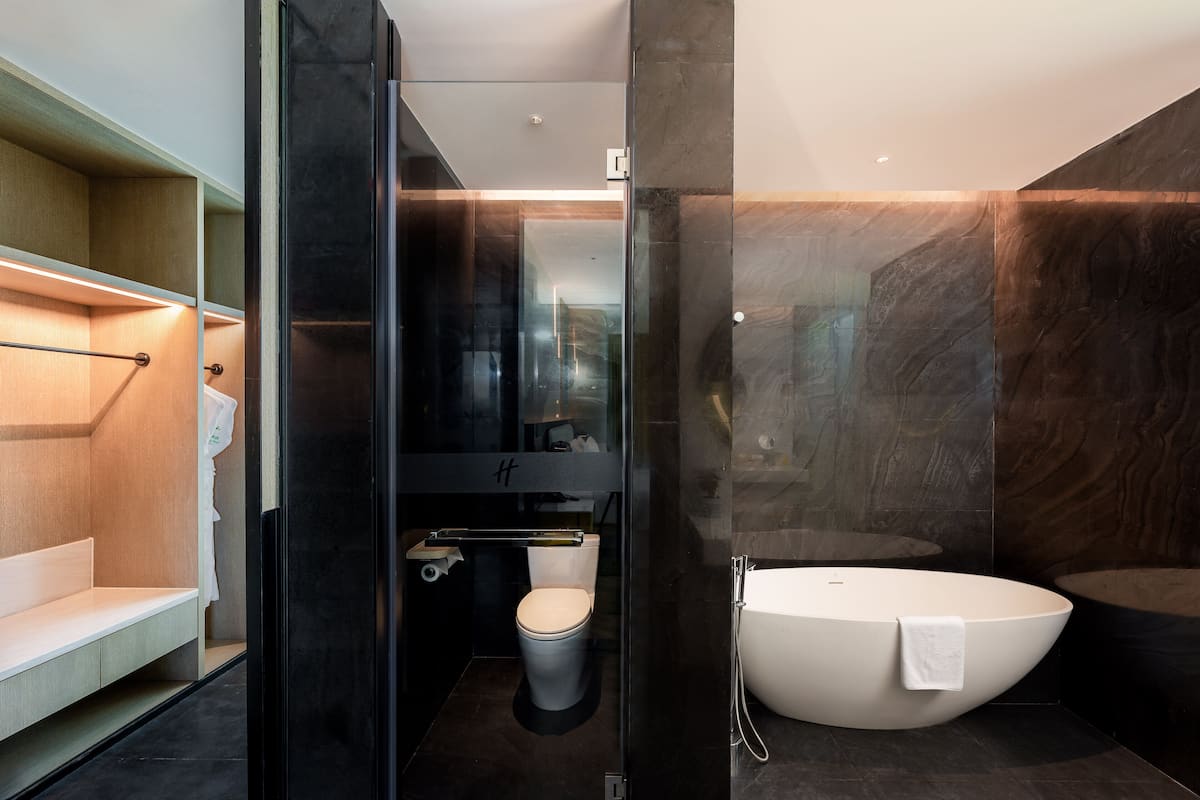 A modern bathroom with a toilet, a bathtub, and a glass-enclosed shower area.