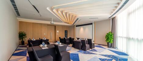 A conference room with a geometric carpet, a large screen, and a modern ceiling design.