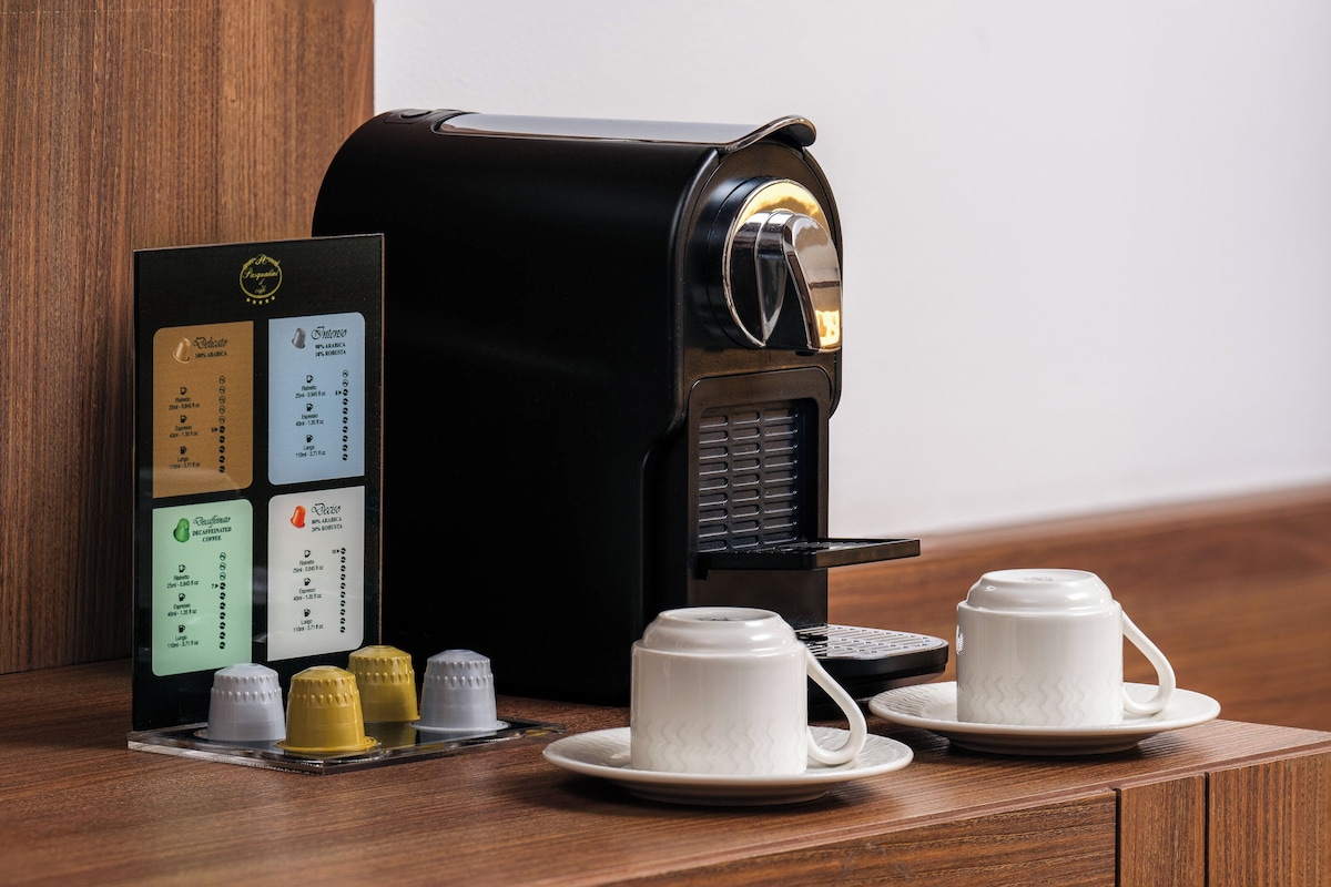 A coffee machine with a menu card and two white cups on a wooden surface.