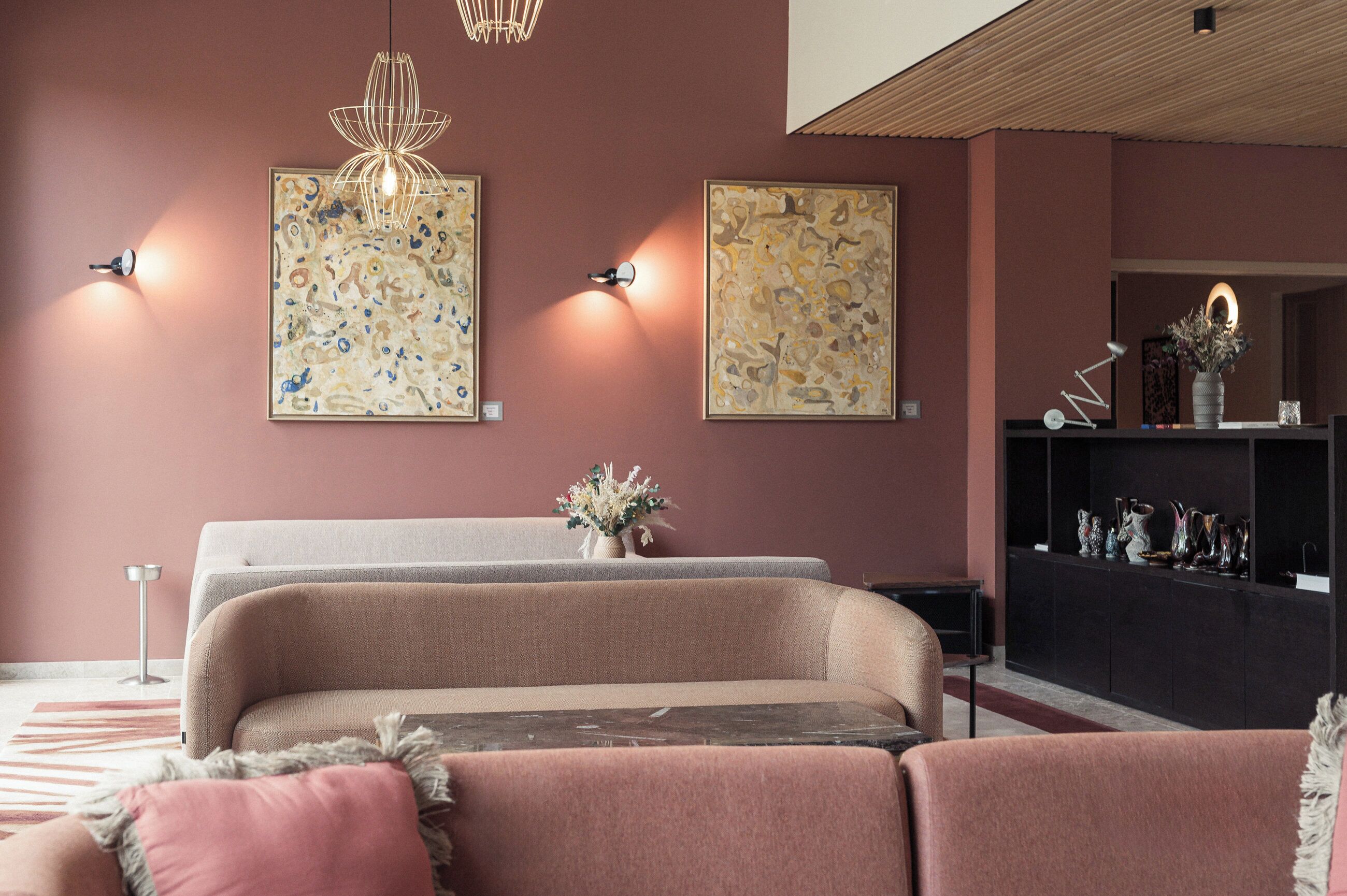 A modern living room with a sofa set, a console table with decorative items, and abstract wall art.