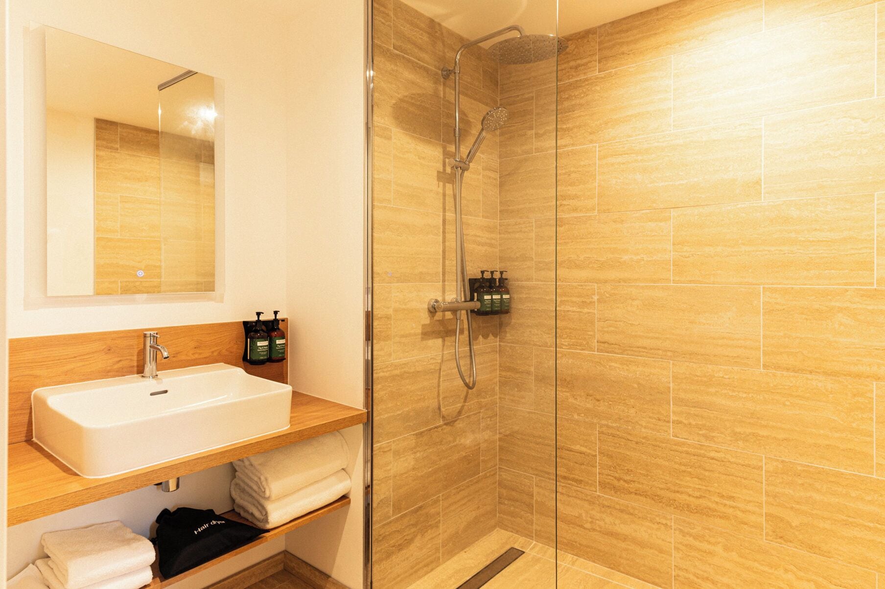A bathroom with a glass-enclosed shower, a sink, and a mirror.