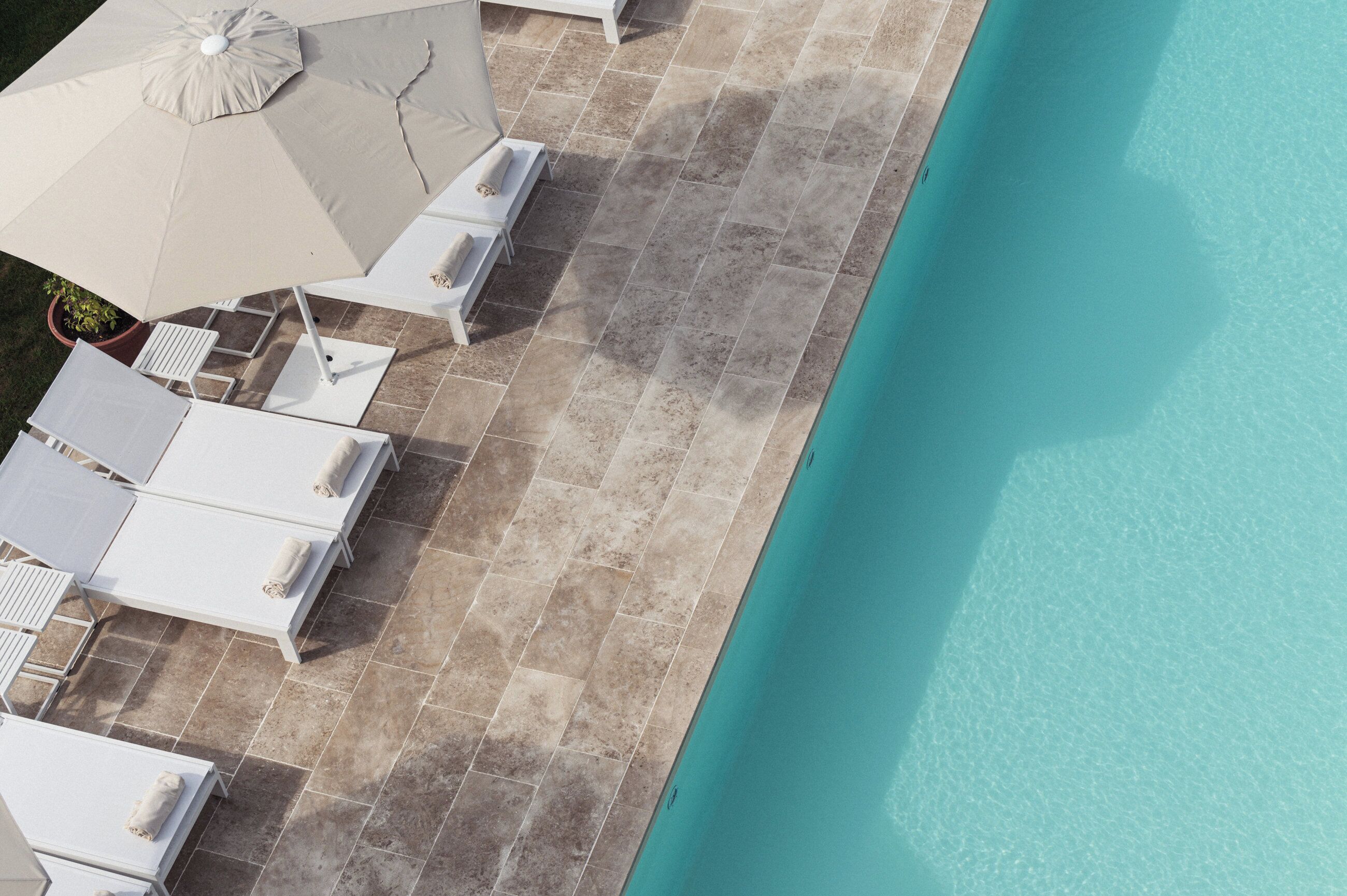 Un área junto a la piscina con sillas de descanso y sombrillas.