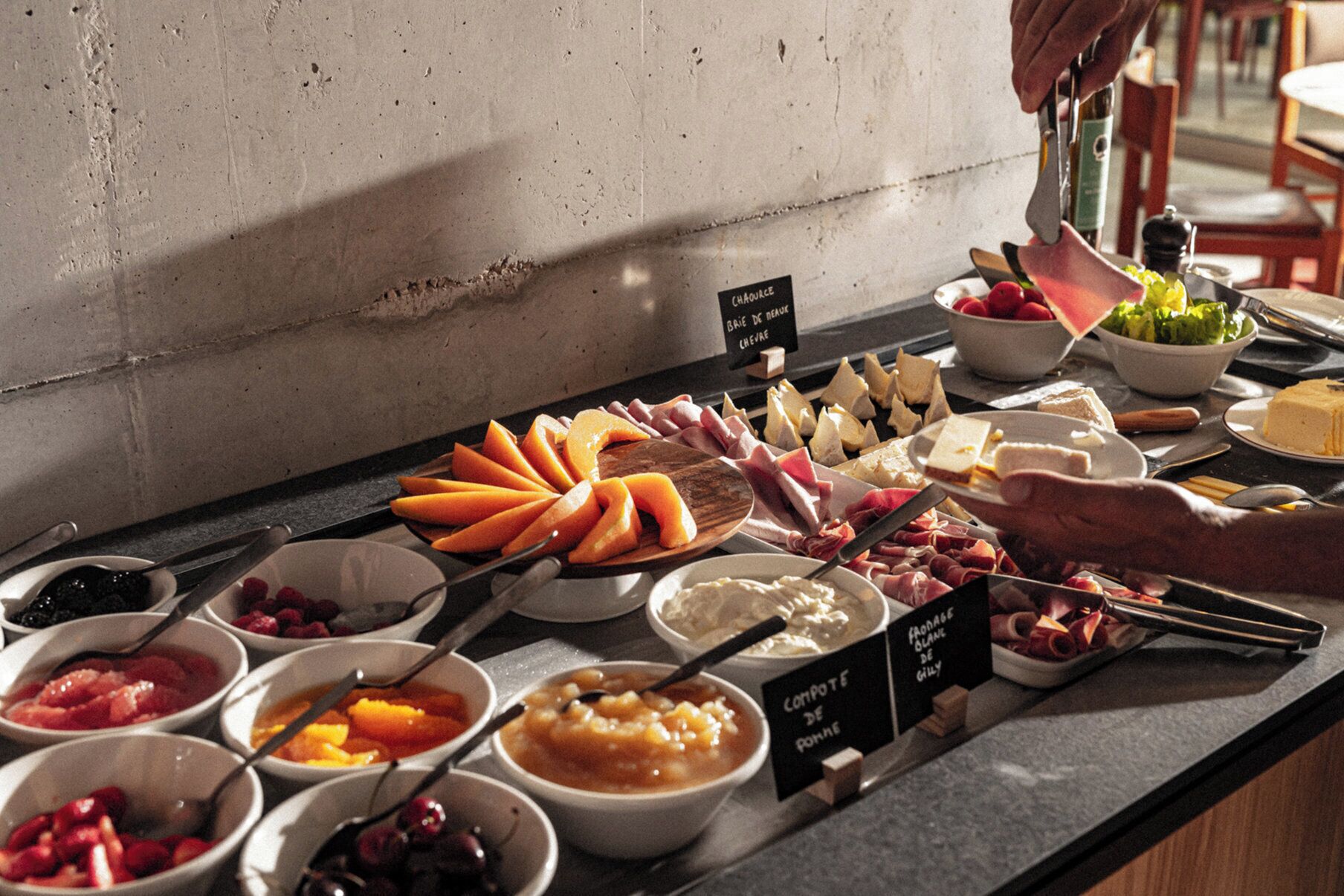 Un bufé con diferentes opciones de comida, incluyendo frutas, quesos y carnes.