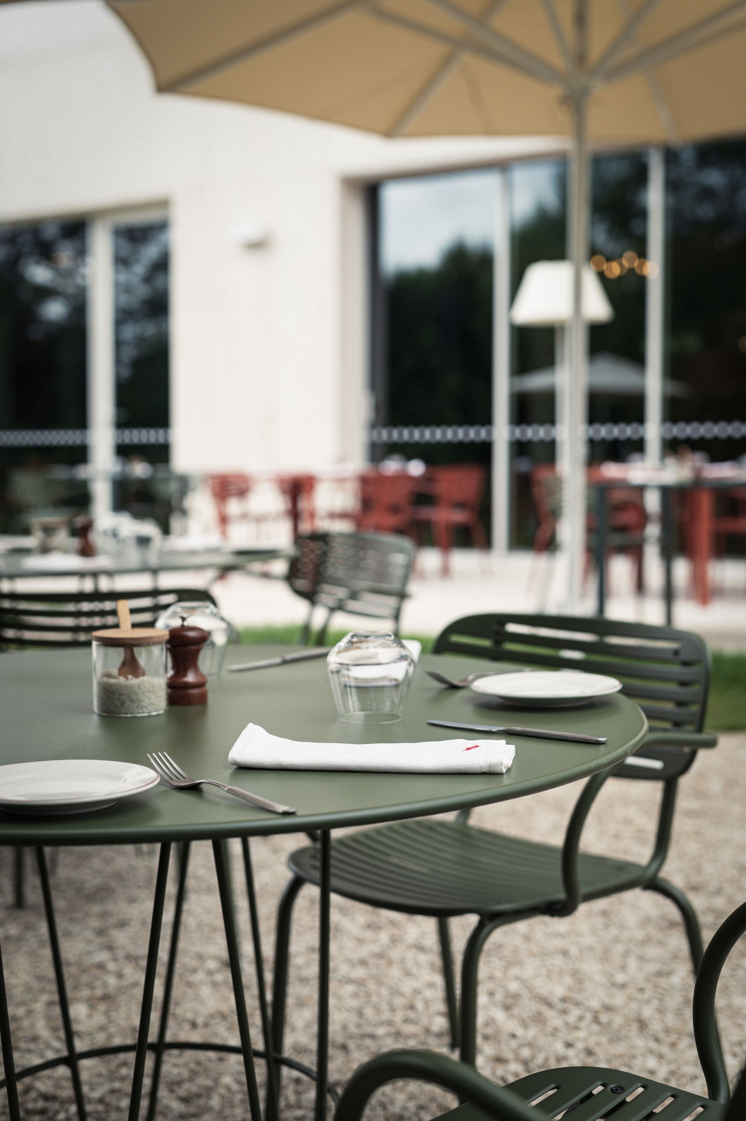 A table set outdoors with plates, cutlery, and a napkin.