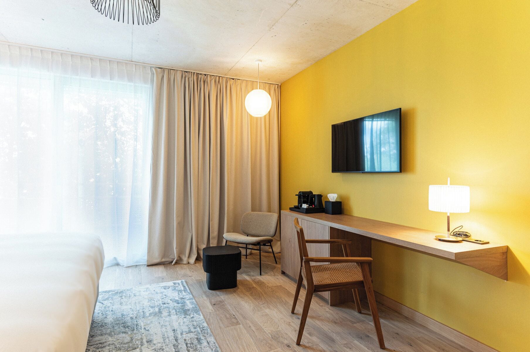 Une chambre d’hôtel comprenant un lit, un bureau avec une chaise, une télévision et une lampe.