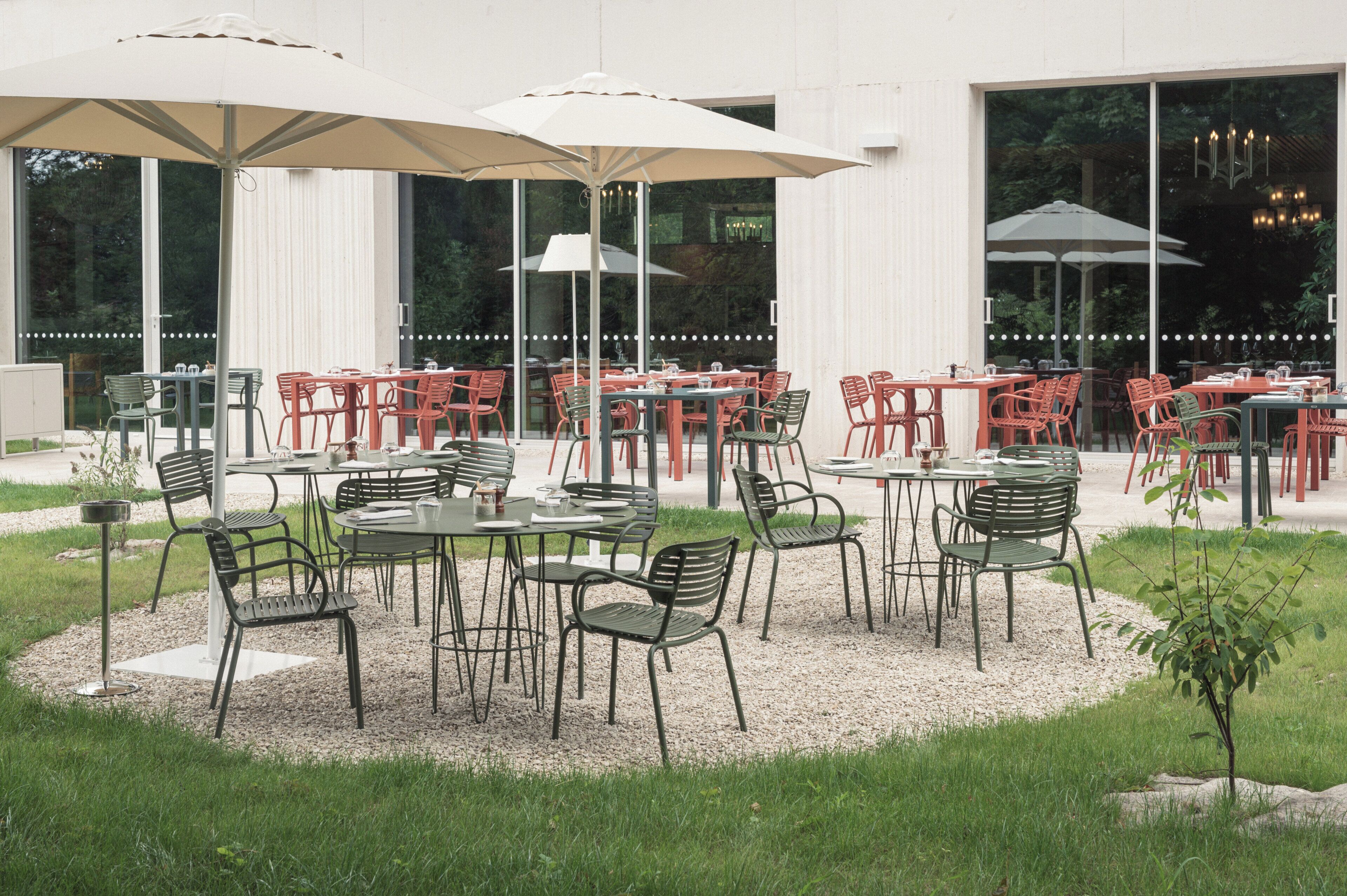An outdoor seating area with tables and chairs, umbrellas, and a view of the building in the background.