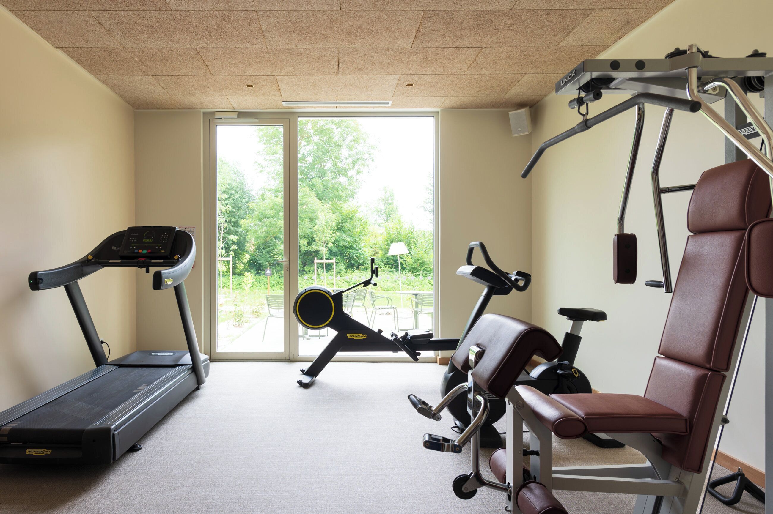 A home gym with a treadmill, stationary bike, and weight bench.
