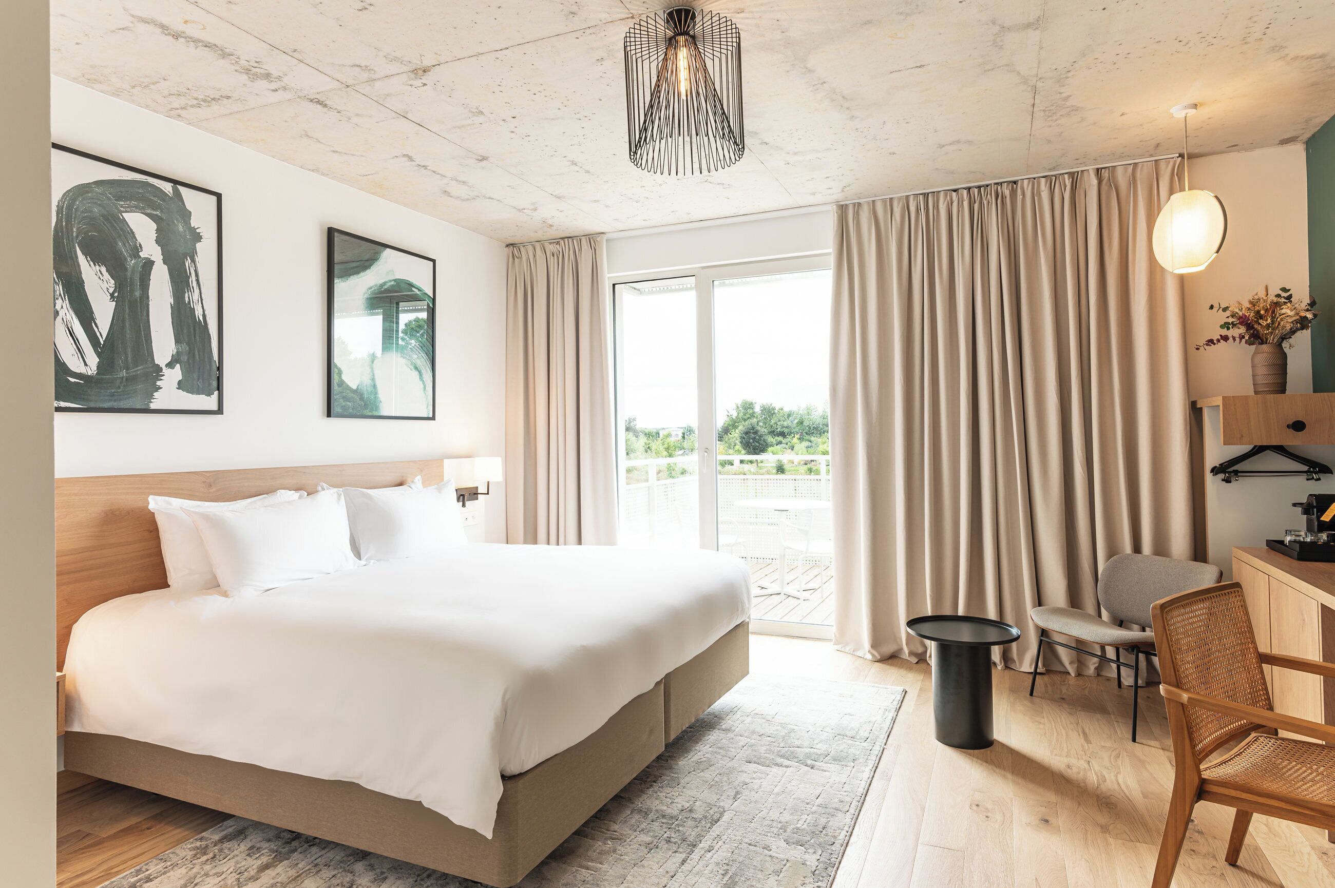 Camera d'albergo con un letto grande, una scrivania con una sedia, un lampadario e vista sull'esterno.