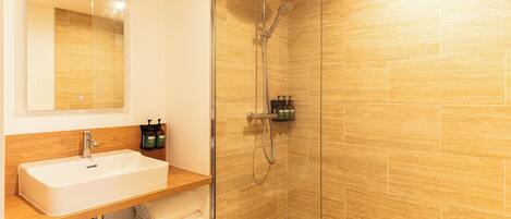 A modern bathroom with a glass-enclosed shower, a white sink, and a wooden vanity.