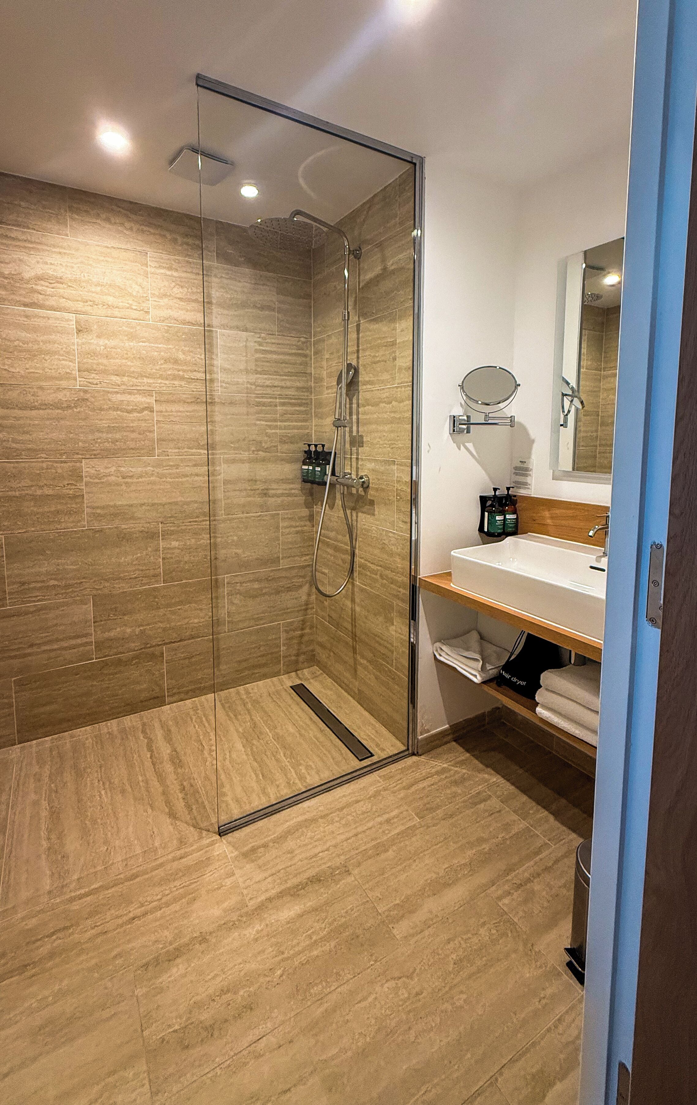 Een moderne badkamer met een douchecabine van glas, een wastafel met spiegel en een wasbak.