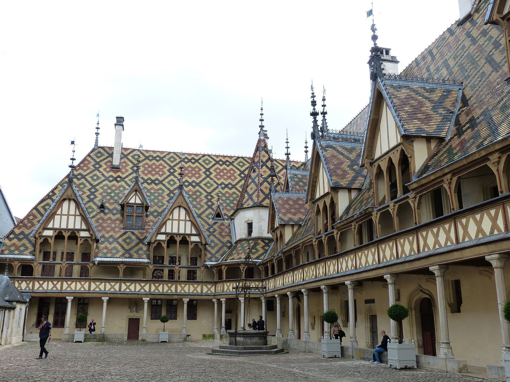 Une cour intérieure avec un bâtiment doté d’un toit orné de motifs et d’une architecture gothique.